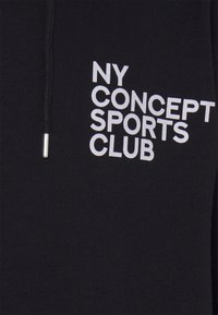 Sudadera negra con capucha que presenta un logo impreso en blanco: "NY CONCEPT SPORTS CLUB." Incluye un cordón con punta metálica, fabricada en una tela suave.