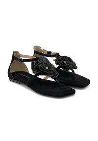 Sandali in suede neri con suola piatta, caratterizzati da un'applicazione floreale e da cinturini alla caviglia. Design a punta arrotondata, texture liscia in tutto.
