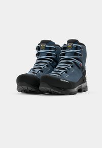 Scarpe da trekking blu in suede con suole in gomma nera, punta rinforzata e lacci azzurri. Presentano un logo sul tallone e ganci robusti per l'allacciatura.