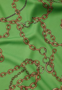 Grüner Stoff mit einem Kettenmuster in Brauntönen. Das Design umfasst verschiedene Kettenglieder und kreisförmige Akzente mit einer glatten Textur.