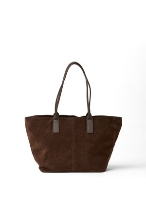 Bolso tote de ante marrón oscuro con dos asas largas de cuero, forma rectangular y interior espacioso sobre un fondo blanco liso.