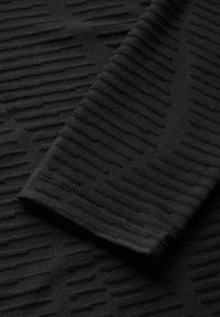 Schwarzer Stoff, der ein strukturiertes Muster mit erhobenen horizontalen Linien zeigt. Glatte Textur, Nahaufnahme des Materials und der Nähte.