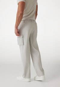 Ljusgrå ribbade cargobyxor med avslappnad passform, elastisk midja, sidfickor och en framträdande varumärkesetikett på cargofickan.