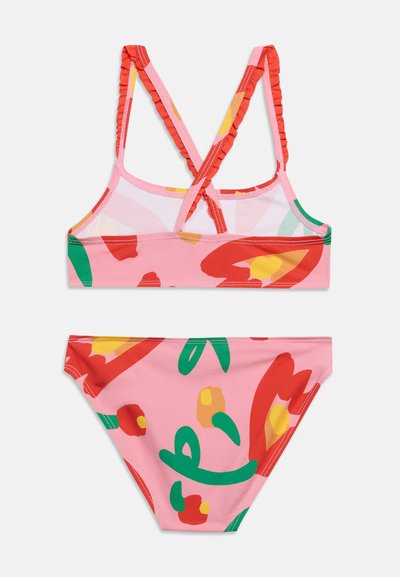 Σετ μαγιό για κορίτσια, δύο κομματιών, με ροζ βάση, κόκκινα, πράσινα και κίτρινα λουλουδάτα σχέδια και βολάν στους διασταυρωτούς ιμάντες στους ώμους στο πάνω μέρος.