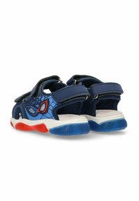 Sandalias azules con un diseño de telaraña, acentos rojos y azules, correas de Velcro ajustables y una suela texturizada para mayor agarre.