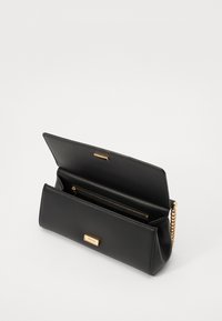Pochette en cuir noir avec des accents en métal doré, dotée d'un compartiment zippé et d'une bandoulière en chaîne. Extérieur texturé, forme rectangulaire.