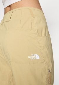 Khaki hlače z mehkim tekstilom, z zadnjim žepom in belim logotipom The North Face. Vključujejo podrobnost stranskega žepa na zadrgo.