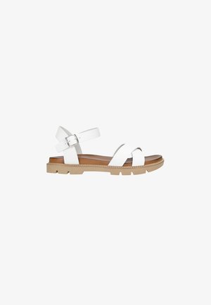 White leather sandal featuring cross-strap design, ankle strap with metal buckle, and a brown cushioned footbed. Textured rubber outsole.