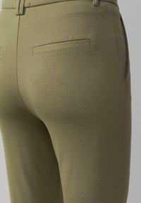 Pantalons ajustés vert olive avec une texture lisse, dotés de deux poches arrière et d'un design moulant qui épouse la silhouette.