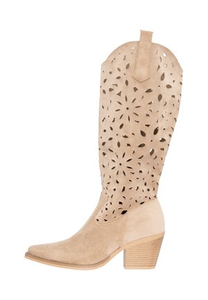 Beige suède cowboystoflaars met bloemenuitsnijdingen, gestapelde houten hak en licht puntige neus.