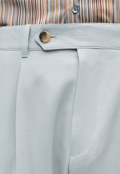 Φωτεινό γαλάζιο παντελόνι με εφαρμογή, με κλείσιμο πλαϊνής ταινίας με κουμπιά, φορεμένο με πολύχρωμο ριγέ πουκάμισο εκπτυσσόμενο μέσα.