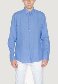 Camicia a maniche lunghe a righe di colore blu chiaro, con colletto e polsini a bottone. Il tessuto appare strutturato con sottili linee verticali.