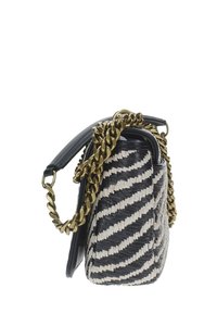 Borsetta intrecciata con un motivo zigzag nero e crema, dotata di una tracolla in catena dorata e una forma strutturata. Texture liscia e dettagli in pelle.
