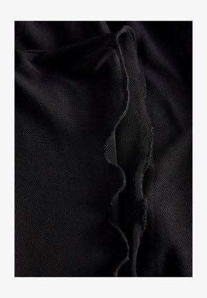 Țesătură neagră cu un detaliu texturat și ondulat la margine. Materialul pare ușor și ușor adunat, evidențiind o suprafață netedă.