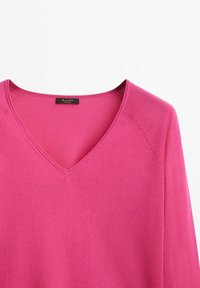 Pull à col en V et manches longues de couleur rose vif, en maille douce et lisse avec des coutures détaillées le long des épaules.