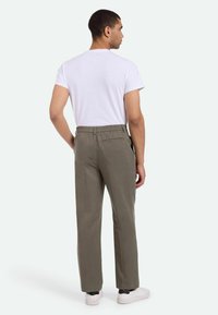 Pantalones ligeros de hombre en color verde oliva, de corte recto, con cinturilla elástica y bolsillo trasero, combinados con una camiseta blanca lisa.