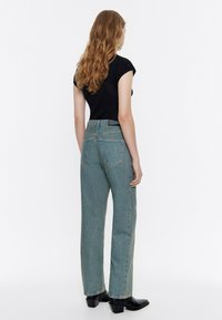 Sinised denim teksad, millel on lõdva istuvus, kõrge vöökoht ja laiali puistatud glittersingid. Ühendatud musta külgkorviga topi ja mustade kontsakingadega.