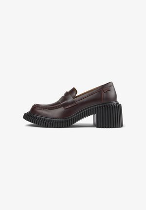 Mocasin de cuero marrón con punta redondeada, que presenta un diseño plisado y un tacón negro grueso y estriado para mayor estabilidad.