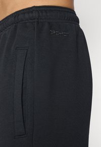 Black Dri-FIT sweatpants featuring a soft texture, elastic waistband, and side pockets, designed for comfort and moisture management.
