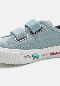 Baskets en denim bleu avec des brides Velcro, semelle en caoutchouc blanche et motifs ludiques de véhicules sur le côté. Présentent un dessus texturé et un bout rond.