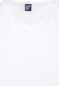 Witte v-hals t-shirt gemaakt van zachte katoen met een gladde textuur. Heeft een klein logo label met de tekst "ALAN RED" bij de halslijn.