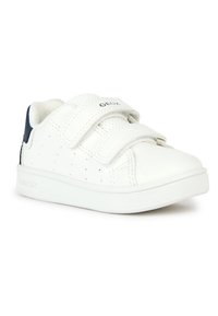 Baskets blanches pour enfants avec deux bandes Velcro, côtés perforés et une languette de talon bleu marine, sur fond blanc.