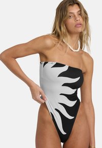 Sorthvitt heldraktbadedrakt med skulderfri design og solstrålemønster. Laget av teksturert stoff med høyt utskårne benåpninger.