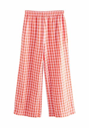 Pantalon ample avec taille élastique et motif vichy orange et blanc sur fond blanc.