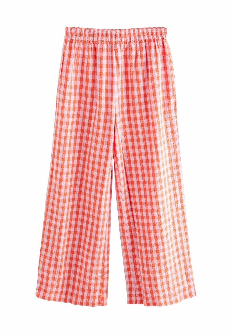 Pantalon ample avec taille élastique et motif vichy orange et blanc sur fond blanc.