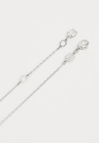 Collier en chaîne argentée avec des maillons ovales et hexagonaux, présentant un gemme rectangulaire clair et une fermeture à mousqueton.