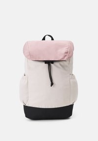 Sac à dos avec rabat supérieur rose clair et corps beige, doté d'un fond noir et d'une fermeture à cordon ajustable ; poches latérales incluses.