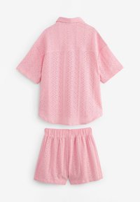 Rosarutig kortärmad skjorta och shorts-set tillverkat av lätt tyg med ögondetaljer. Skjortan har krage; shortsen har resårmidja.