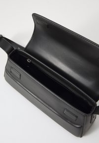 Černá kožená kabelka v obdélníkovém tvaru, hladká textura a vnitřní kapsa se zacvakávacím zapínáním; minimalistický design.