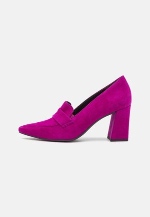 Zapato de tacón alto de ante morado con tacón bloque y detalle de tira en la parte delantera, visto de lado sobre un fondo blanco.