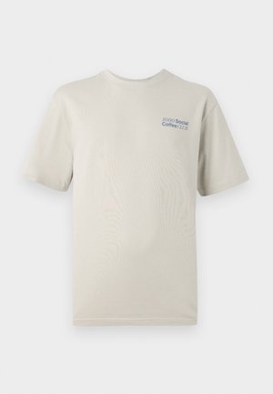 Cămașă cu mâneci scurte de culoare bej deschis, realizată din bumbac moale, având un imprimeu de text albastru "SOHO Social Coffee CLUB" pe partea stângă a pieptului.