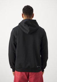 Sudadera negra de tejido suave, con una gran capucha, puños acanalados y cordones ajustables. Logo destacado en el dobladillo inferior.