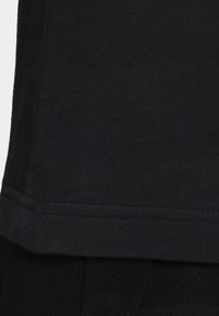 Černé bavlněné tričko s kulatým výstřihem, krátkými rukávy, čistým lemem a hladkou texturou, s jednoduchým švem podél okrajů.