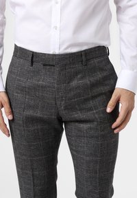 Grå rutmönstrade byxor med en texturerad tygkvalitet, som har en slim fit och sidofickor, i kombination med en vit knapp-up skjorta.