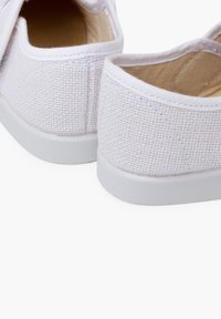 Pantofi slip-on alba din canava cu un exterior texturat și o talpă din cauciuc alb neted. Interiorul este bej, cu detalii de cusătură minime.