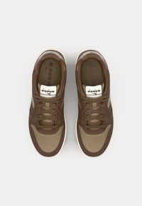 Brown and beige sneakers with a mesh upper, leather accents, round toe, and flat laces. Features a white logo on the tongue.