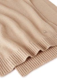 Pletený šátek ve světle béžové barvě, se žebrovanou texturou a jemným logem. Materiál vypadá měkce a teple, ideální do chladného počasí.