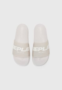 Des sandales blanches à glissière avec des brides transparentes présentant un audacieux marquage blanc "REPLAY MILANO", vues d'en haut sur un fond uni.