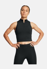 Svart zippered träningskort topp med hög krage, åtsittande design och slät textur, matchat med svarta leggings.