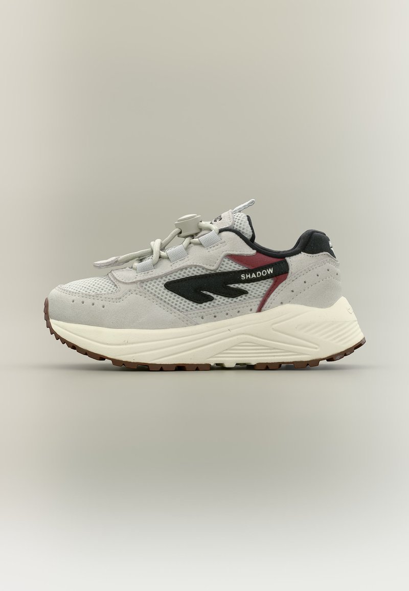 Világosszürke sportcipő fekete és bordó részletekkel, vastag fehér talppal, fekete "SHADOW" feliratos logóval és fűzőzáras megoldással, balra néz.