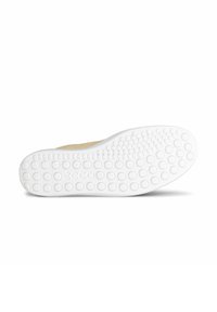 Semelle de chaussure avec une base en caoutchouc blanc présentant un motif texturé et à pois pour une meilleure adhérence. Partie supérieure lisse beige partiellement visible au niveau du talon.