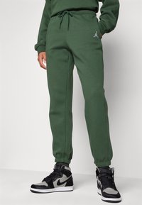 Groene sweatpants met een elastische tailleband en manchetbijsnijdingen, met een klein wit Jordan-logo op het linkerpijp.
