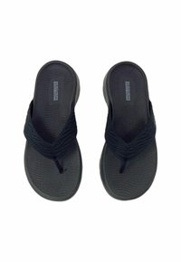 Zwarte slippers gemaakt van gestructureerd rubber met geweven stoffen bandjes. Gevormde voetbed voor comfort en een lichte hakverhoging.