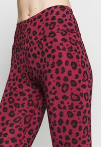 Legíny s vysokým pasem v burgundské barvě se vzorem černého leopardího potisku, s plochými švy a hladkým povrchem.