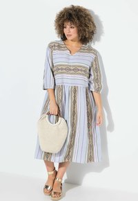 Gestreiftes Midi-Kleid mit V-Ausschnitt, drei Viertelärmeln, gewebtem Stoff und dekorativen Mustern in lila, beige und goldenen Tönen. Begleitet von einer gewebten Tasche.