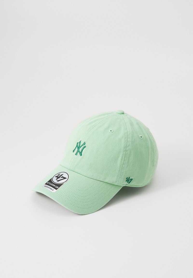 Lys grønn bomull baseballcap med brodert NY-logo og en svart-hvit merkelapp. Har en buet skjerm og justerbar stropp.